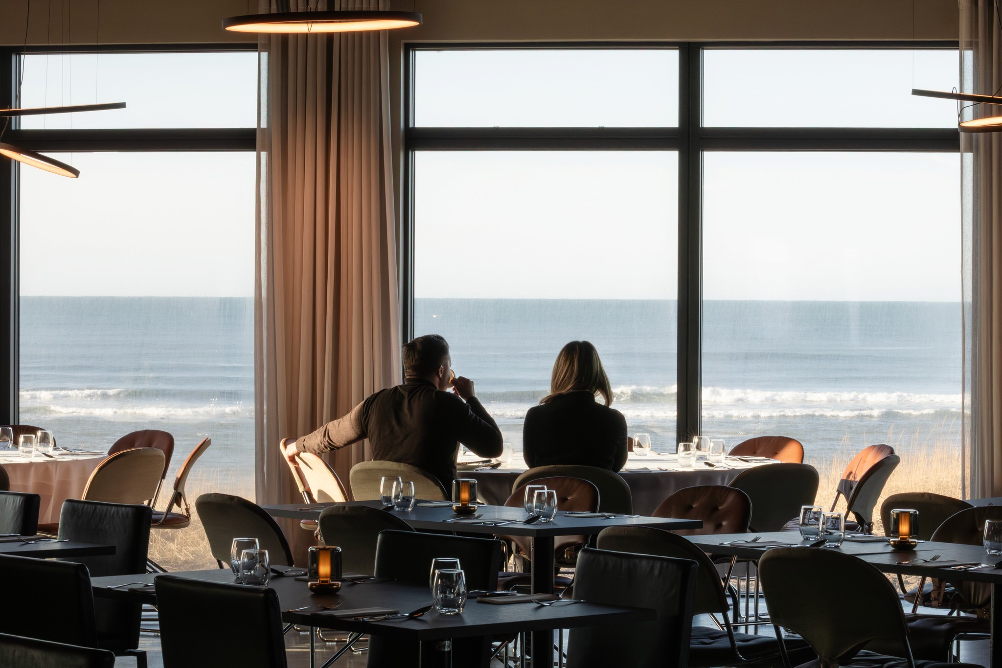 Guests at a window table at ÓMUR, the Atlantic outside